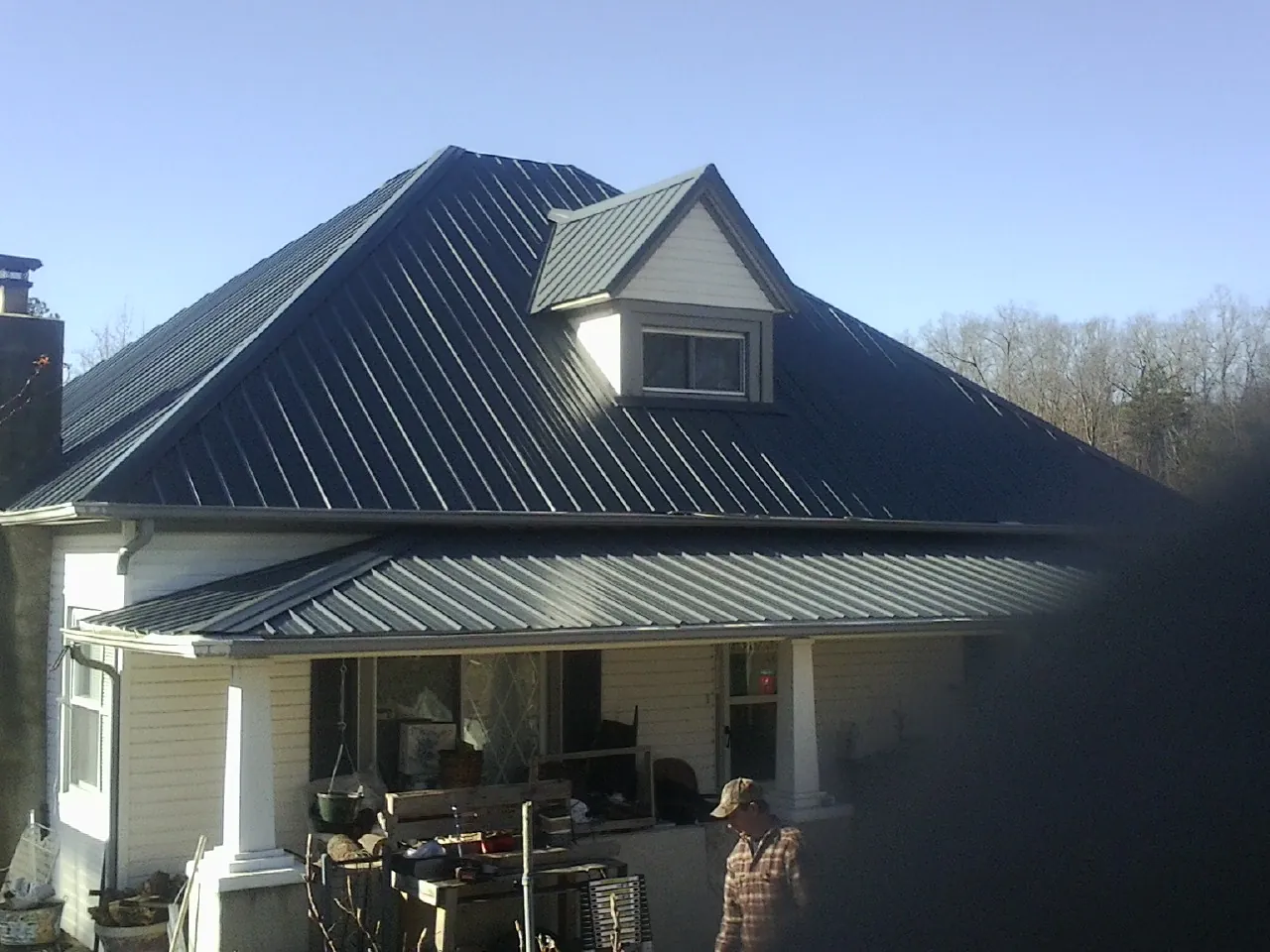 Dark blue standing seam metal roof with a dormer above a front porch in Cherry Tree