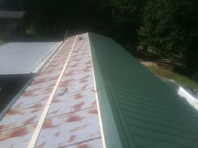 Old rusted panels beside newly installed green metal roofing — Wind Damage Roof Repair by Roofing Brothers in Cherry Tree