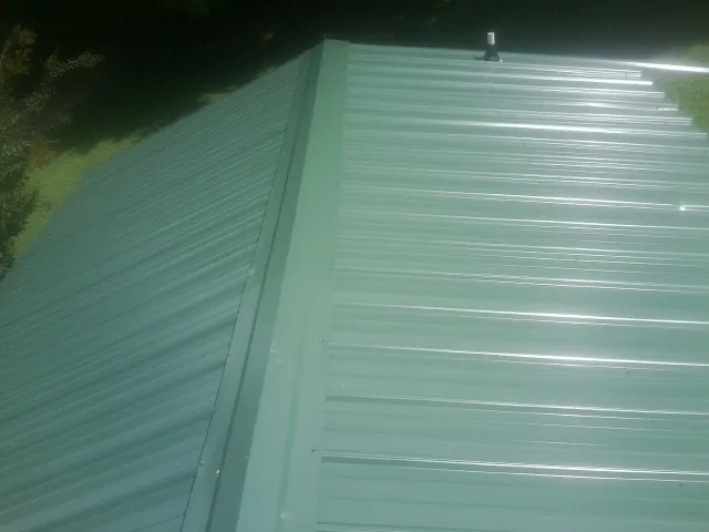 New green metal panels meeting at the ridge of a roof — Flat Roof Repair work by our crew in Cherry Tree