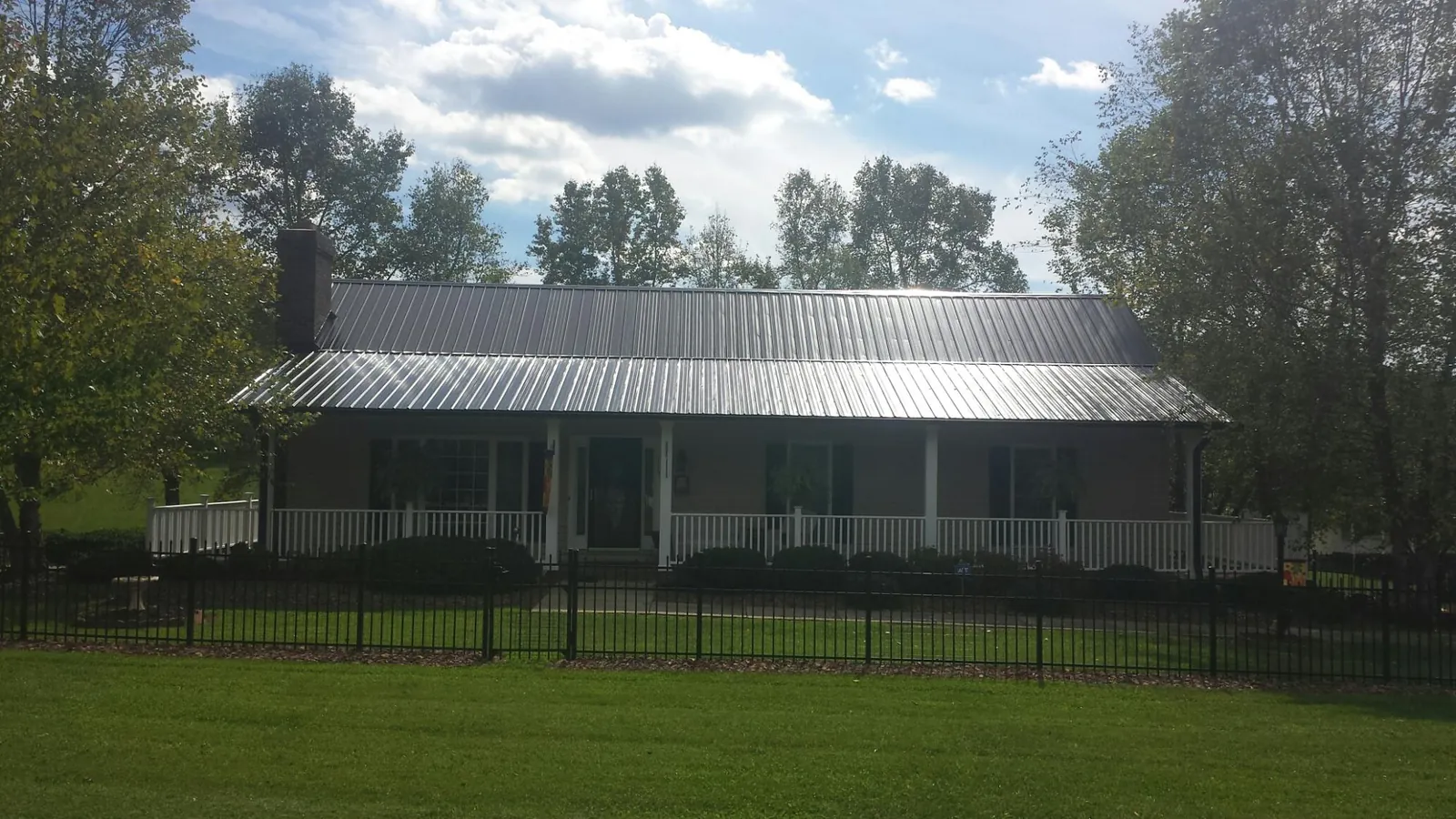 Gray metal roof on a brick ranch with a full width front porch — Gutter Guard Installation work by our crew in Cherry Tree