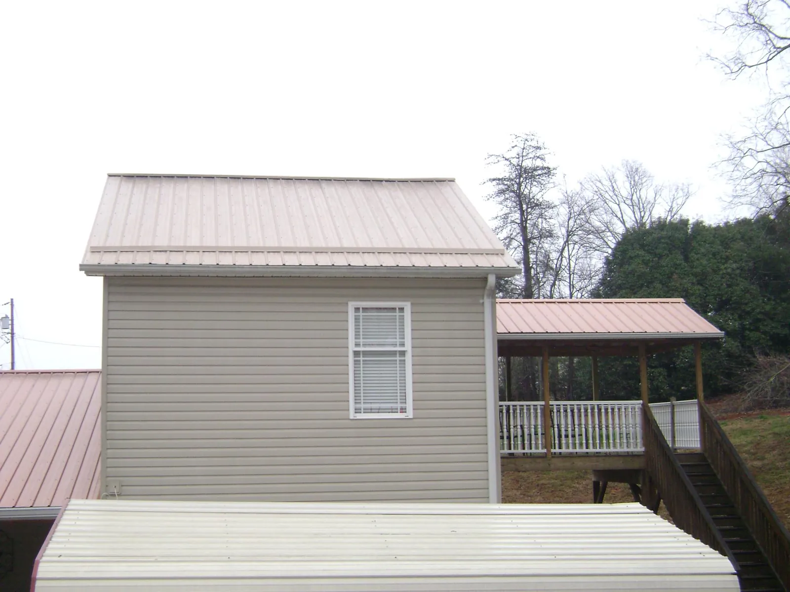 Tan metal roofs on a two story addition and attached porch, from a Roof Replacement job in Cherry Tree