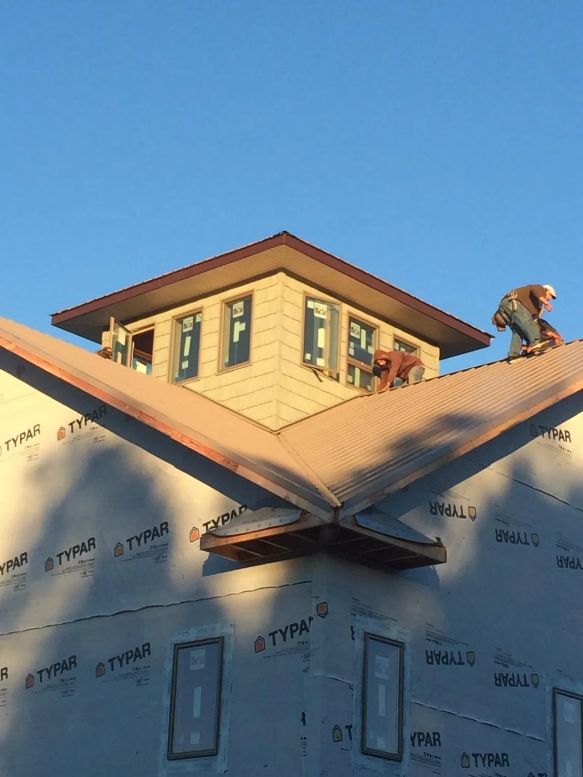 Roofers working around a rooftop cupola on a new metal roof at sunset — Roof Waterproofing in Cherry Tree by Roofing Brothers